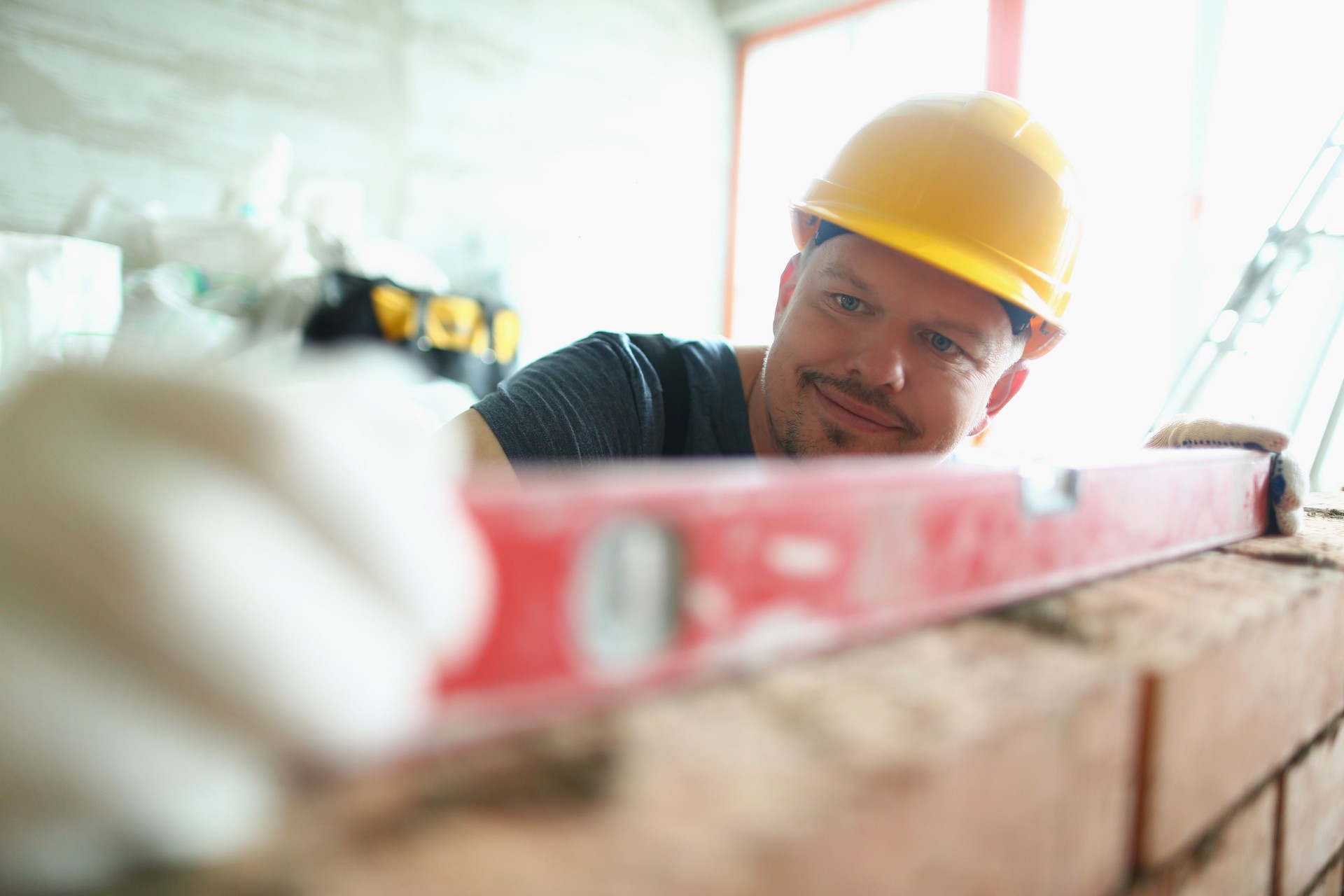 Pedantic man using level tool to measure height of brick wall